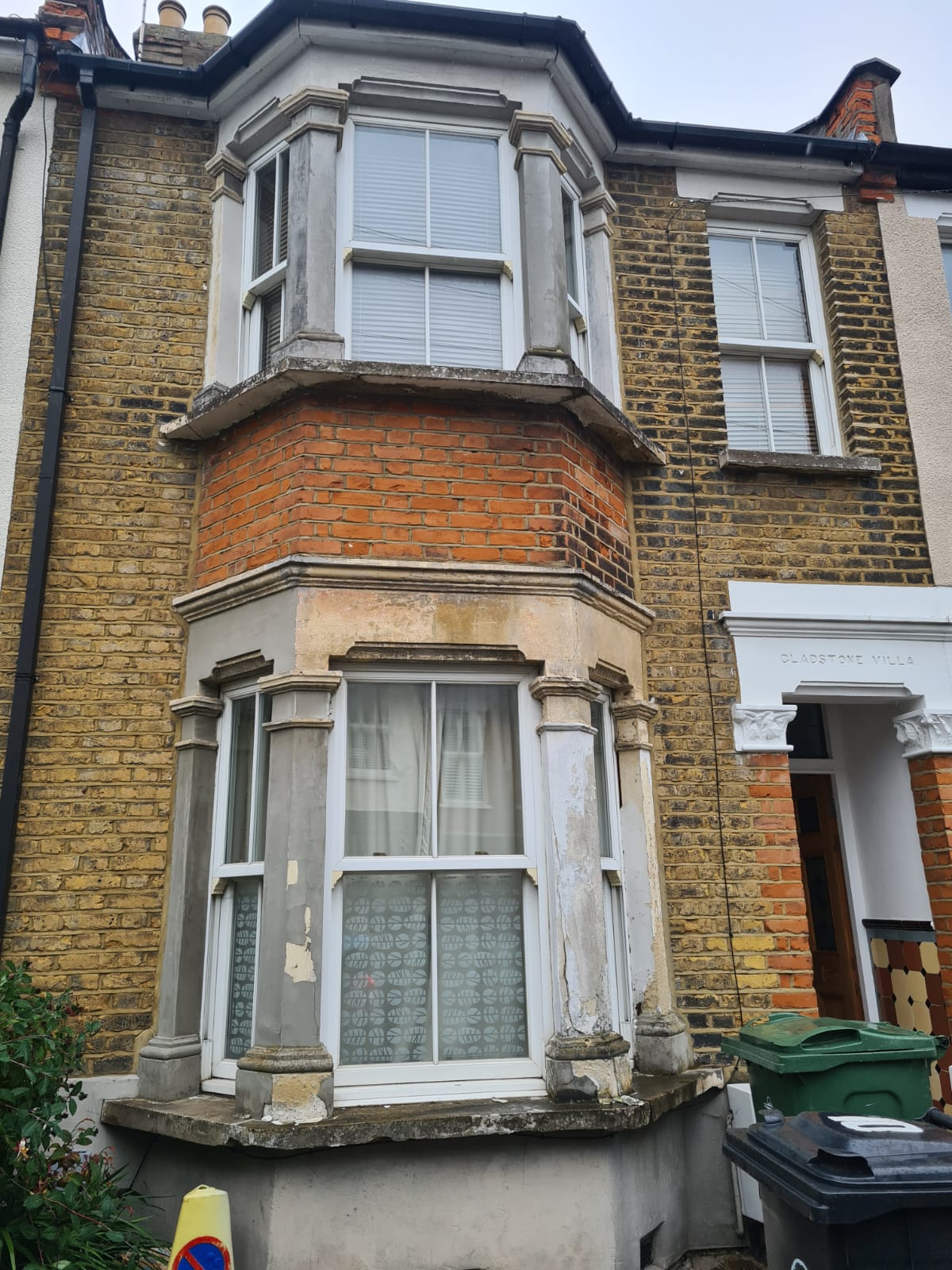 The bay before works, with decayed stucco and spalled render
